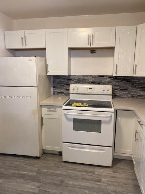 Kitchen featuring white cabinetry with brushed metal pulls, light-toned countertops, multi-tonal linear backsplash, and wood-finish flooring