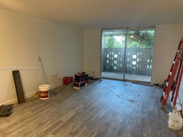 Interior space featuring wood-finish flooring and expansive metal-framed sliding glass doors opening to a concrete masonry unit privacy wall