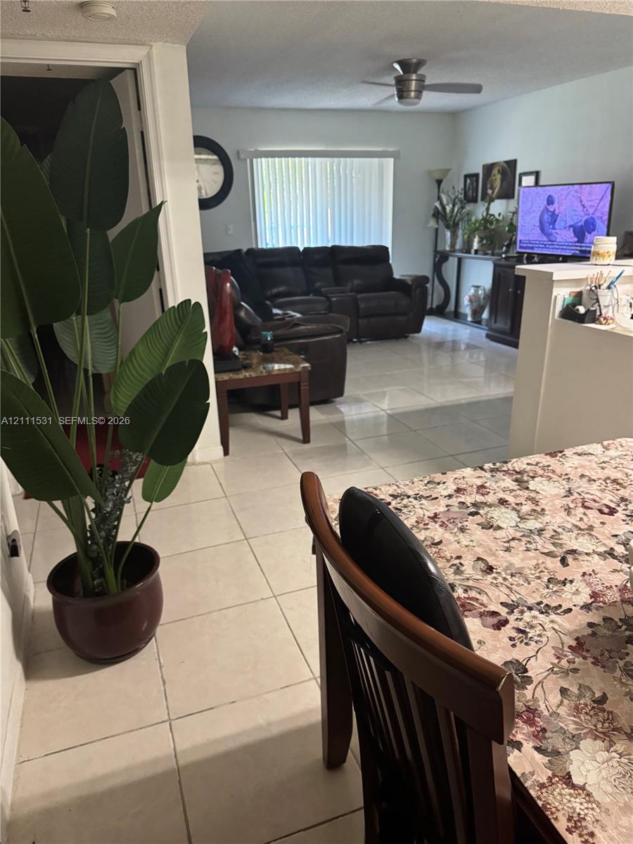 Large-format tile flooring, ceiling-mounted fan, and vertical blind window treatments