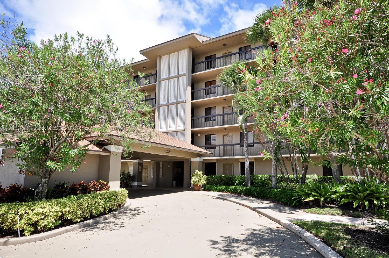 Multi-story exterior featuring a covered porte-cochre, private balconies with railings, and mature landscaping