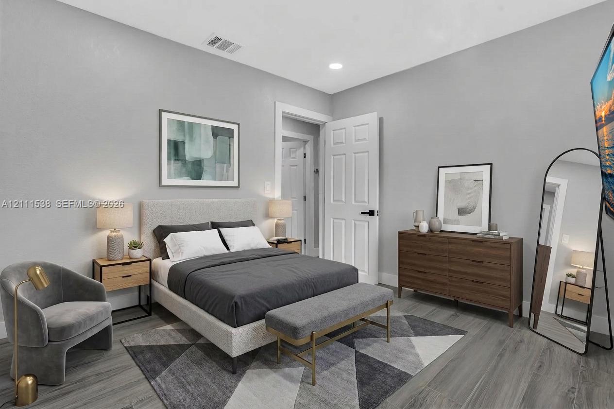 Neutral-toned interior space featuring wood-finish flooring, recessed lighting, and a six-panel door with matte black hardware