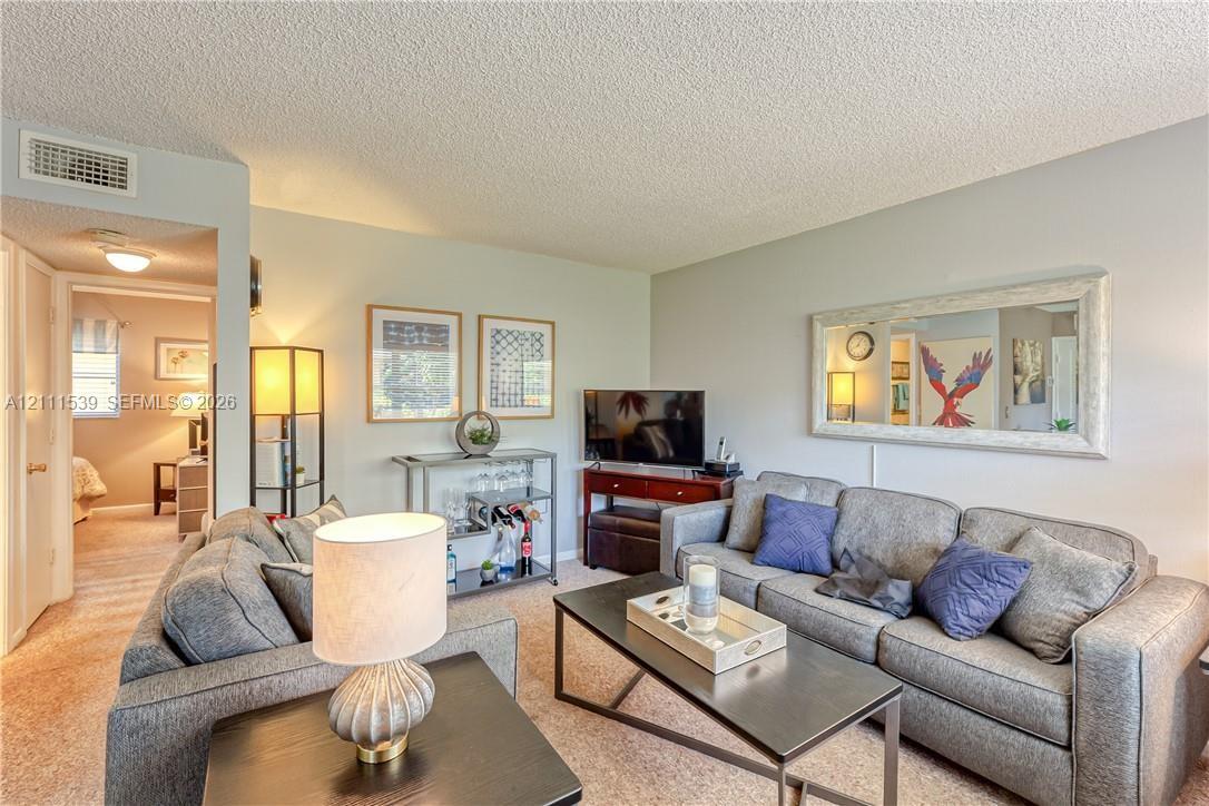 Living area featuring neutral wall paint, wall-to-wall carpeting, and a large, wide-frame wall mirror