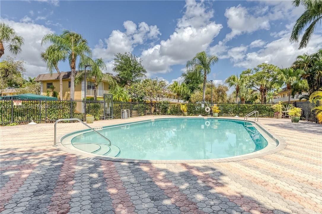 In-ground swimming pool with integrated stair entry, surrounded by patterned stone paver decking and enclosed by black metal perimeter fencing In-ground swimming pool with integrated stair entry, surrounded by patterned stone paver decking and enclosed by black metal perimeter fencing