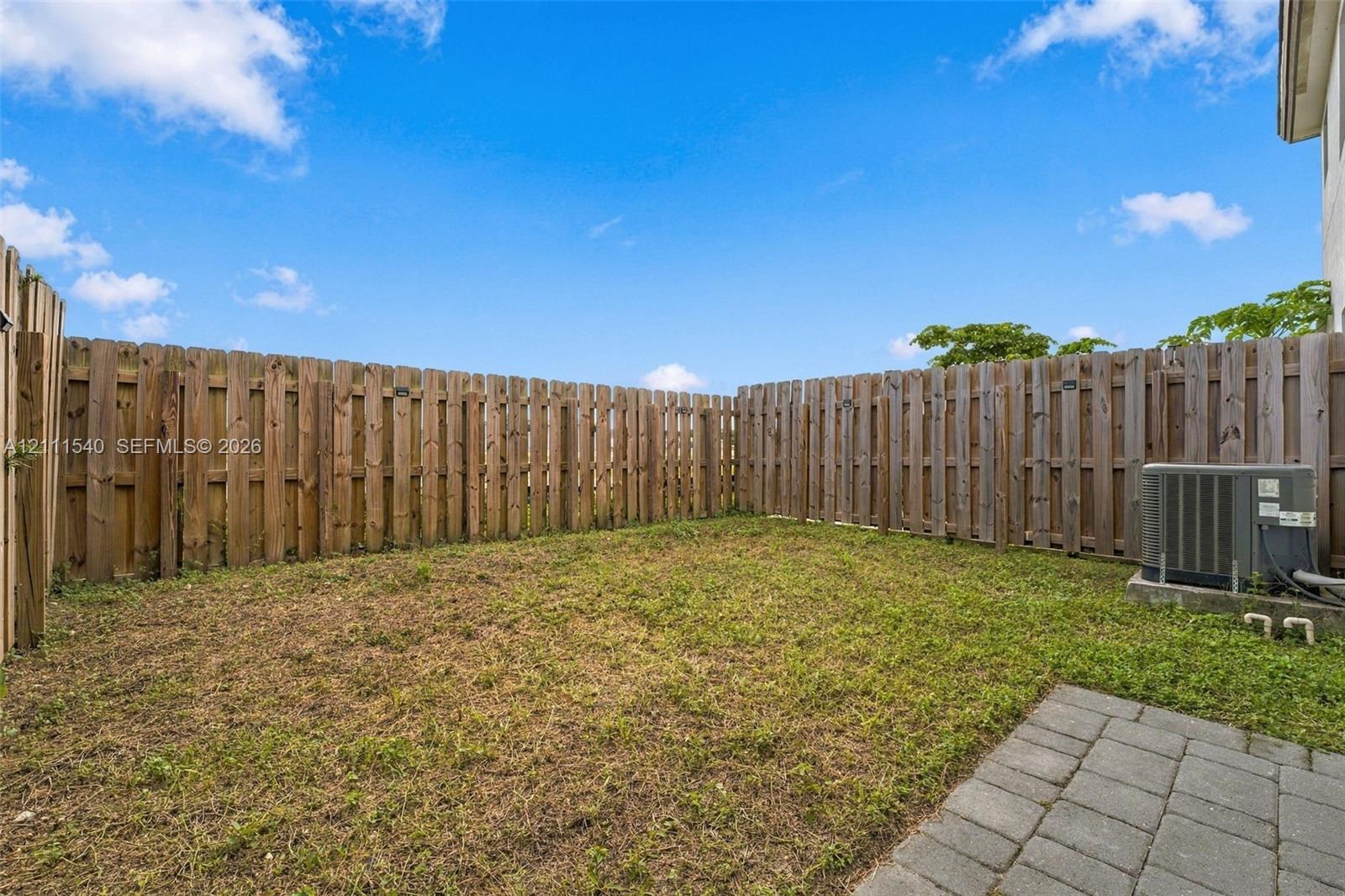Fenced backyard featuring a grass lawn and stone paver patio