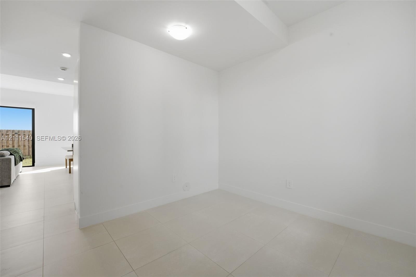 Neutral-toned large-format tile flooring and minimalist white walls with flush-mount ceiling lighting
