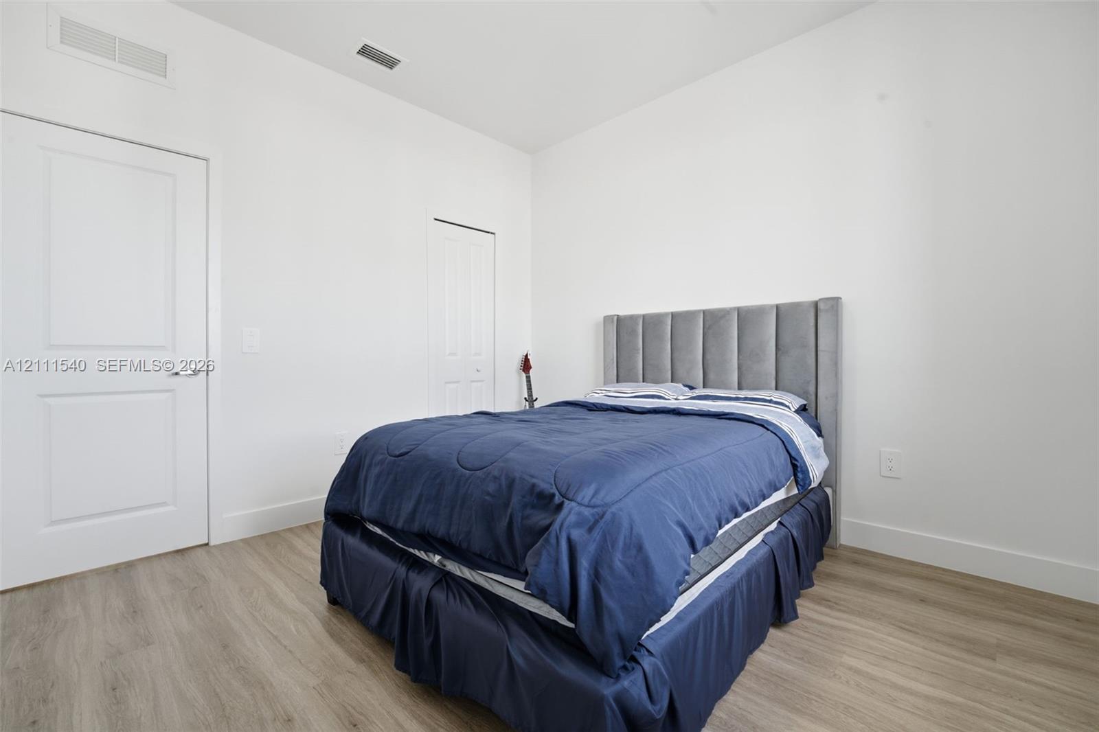 Neutral-toned interior featuring wood-finish flooring, crisp white walls, and multi-panel interior doors