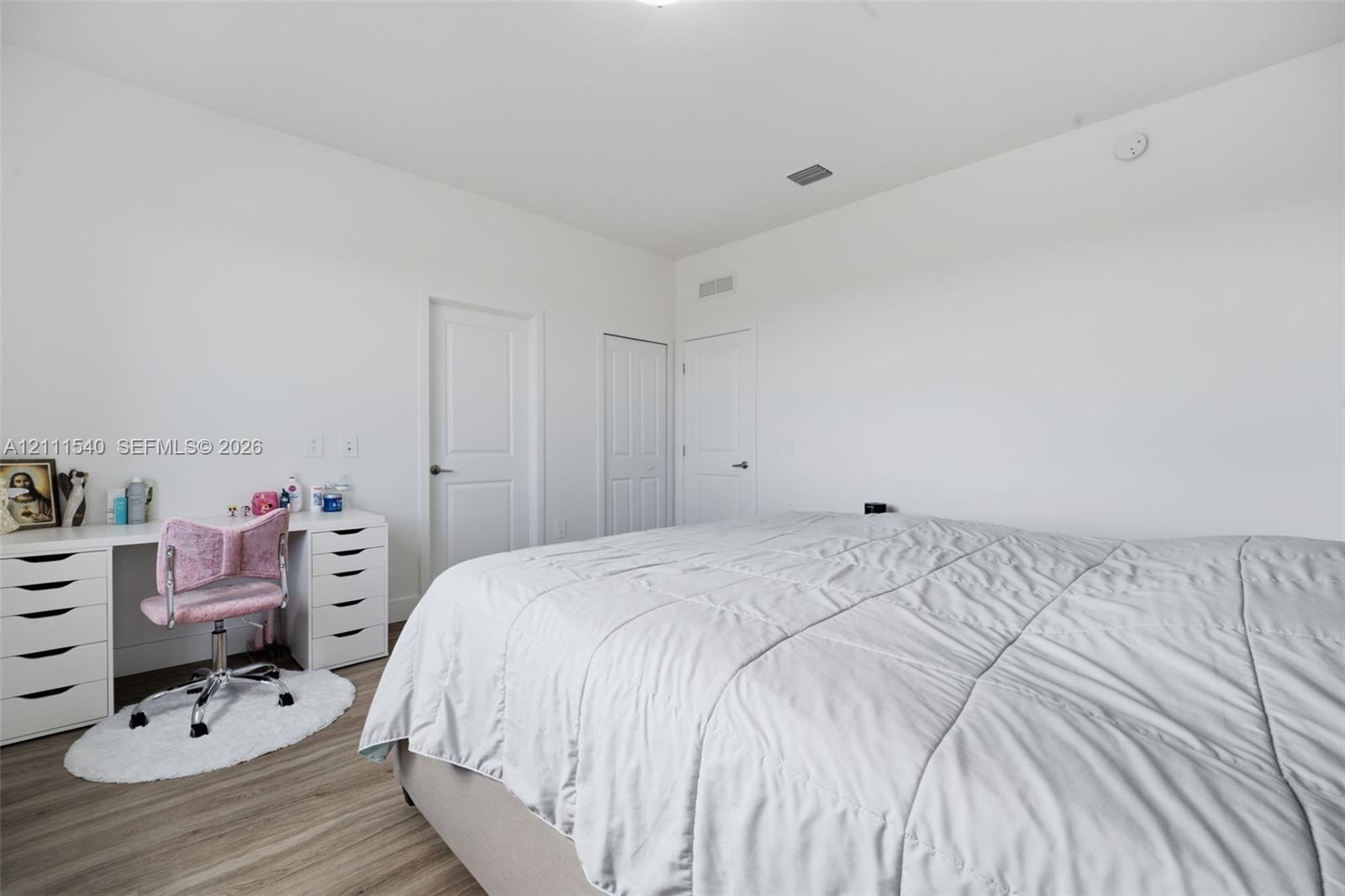 Neutral-toned interior featuring wood-finish flooring, crisp white walls, and multiple solid-core panel doors