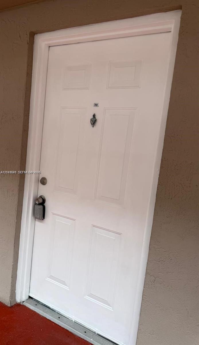 White six-panel entry door featuring a decorative metal door knocker and hardware White six-panel entry door featuring a decorative metal door knocker and hardware