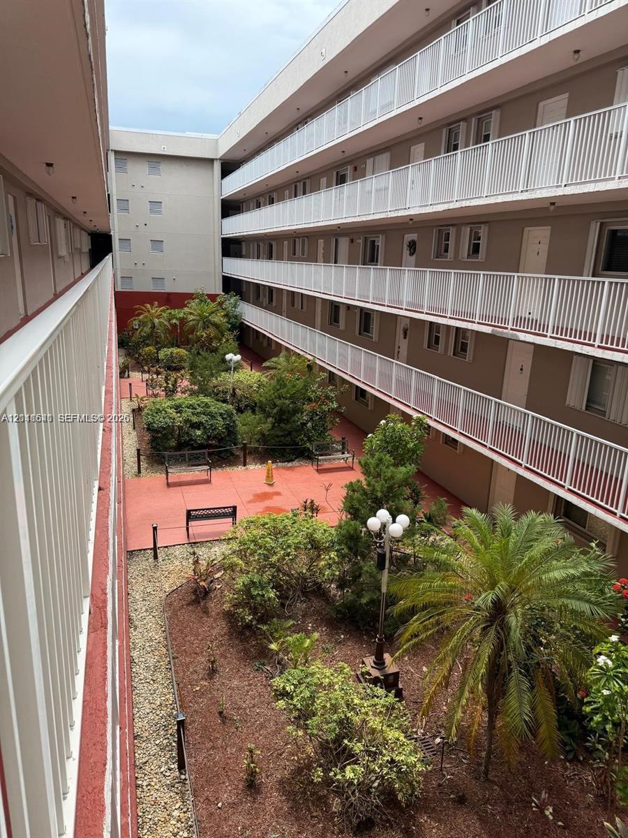 Exterior courtyard featuring multi-level white railed balconies, paved walkways, mature palm landscaping, and decorative outdoor lighting Exterior courtyard featuring multi-level white railed balconies, paved walkways, mature palm landscaping, and decorative outdoor lighting