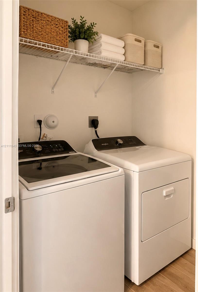 Laundry area featuring wood-finish flooring and integrated wire shelving for storage