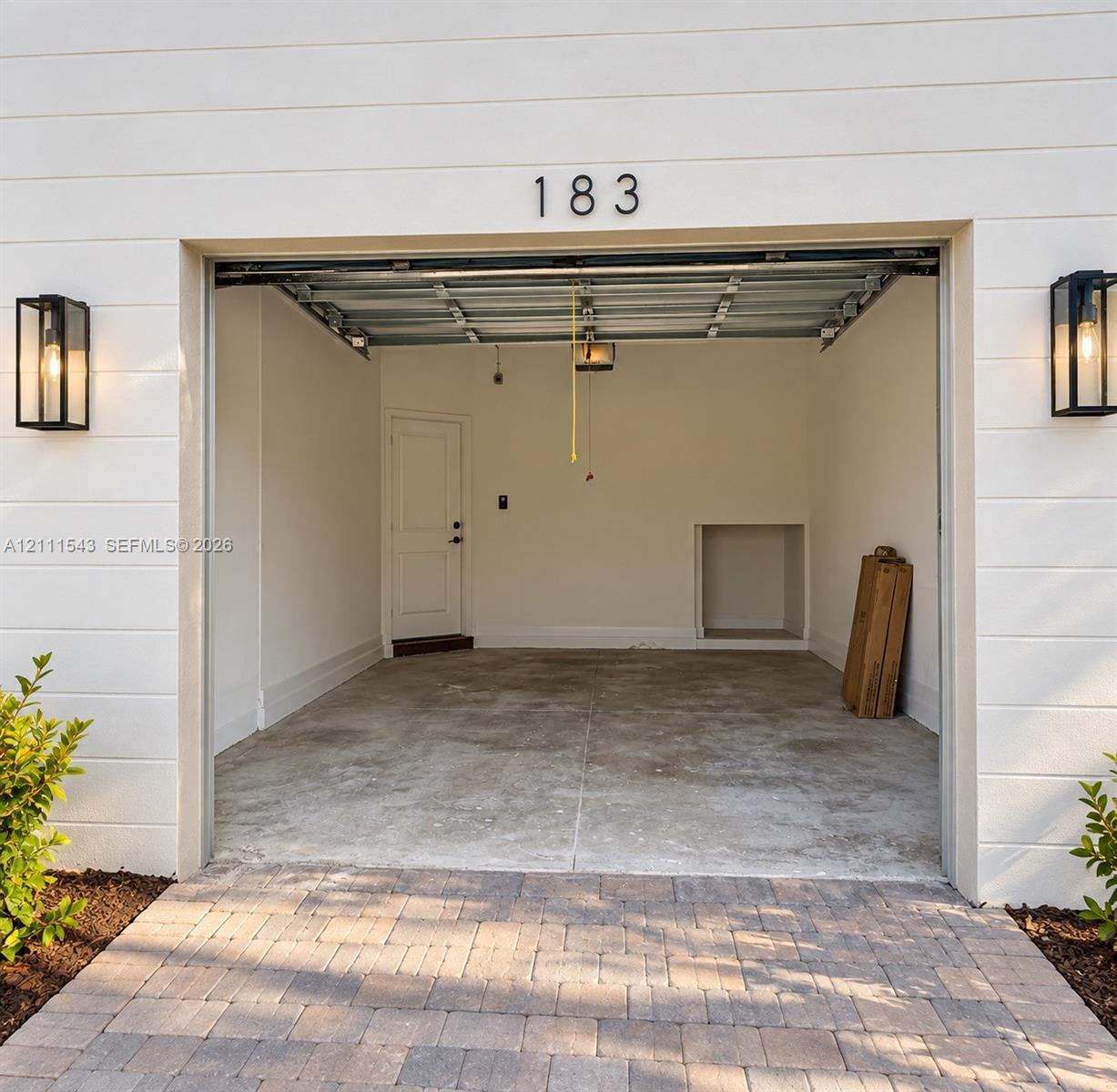 Horizontal lap siding exterior with paver driveway and dual black metal lantern sconces flanking the garage entry
