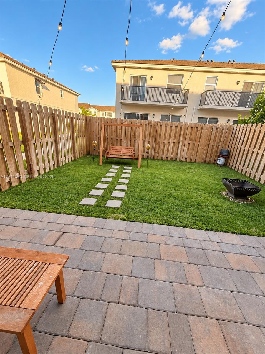 Private backyard featuring stone paver patio, wood privacy fencing, manicured lawn, and stone path