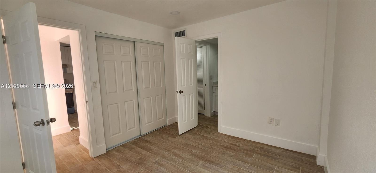 Interior space featuring wood-finish flooring, two sets of panel doors, and recessed lighting Interior space featuring wood-finish flooring, two sets of panel doors, and recessed lighting