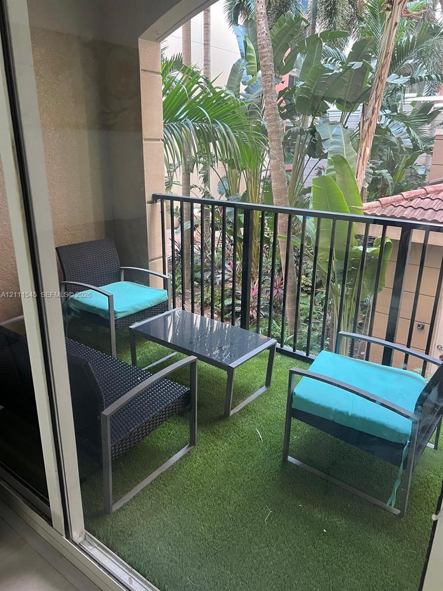 Covered balcony featuring synthetic turf flooring and black metal railing