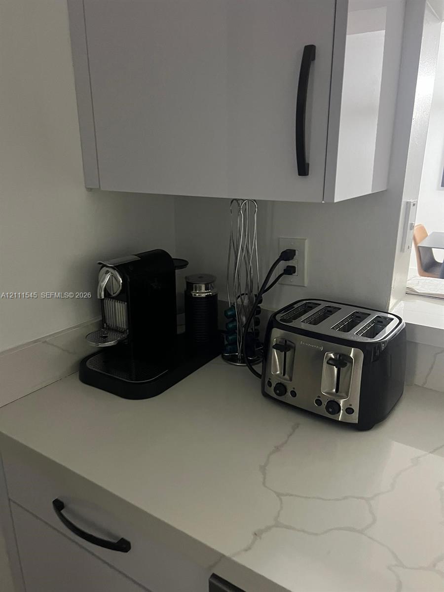 White shaker-style cabinetry with matte black hardware and white stone-patterned countertops White shaker-style cabinetry with matte black hardware and white stone-patterned countertops