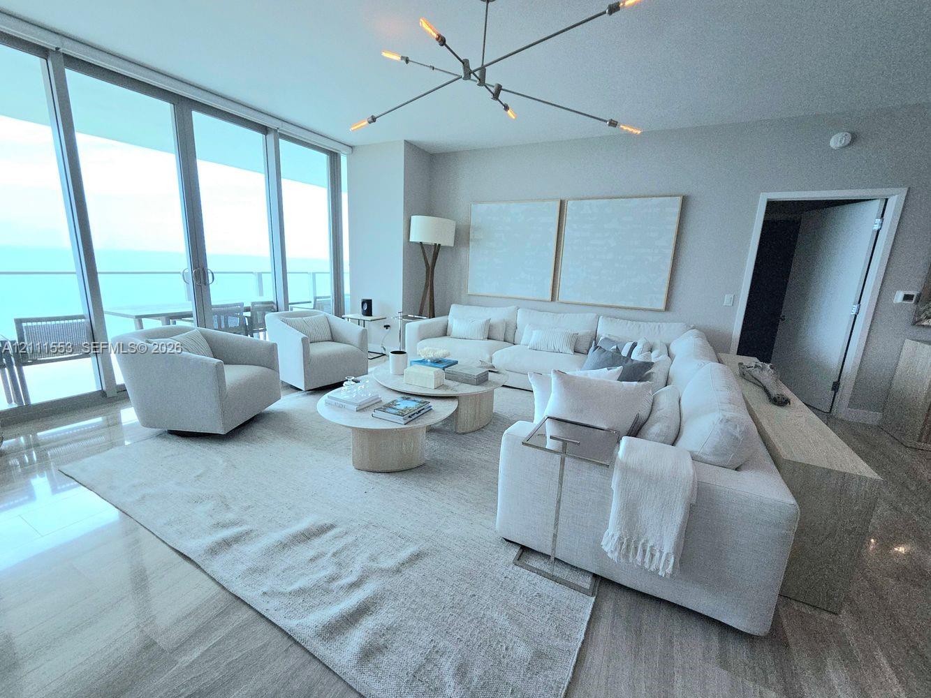 Floor-to-ceiling sliding glass doors, polished stone flooring, and a multi-arm sputnik-style chandelier