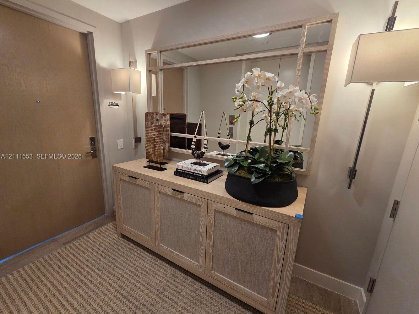 Built-in light-tone wood cabinetry with integrated hardware, framed wall-mounted mirror, and dual vertical wall sconces