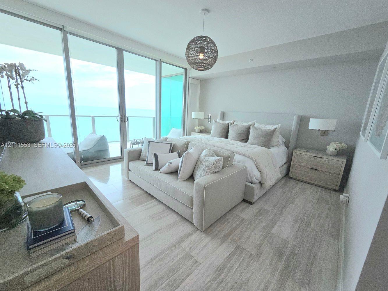 Floor-to-ceiling glass sliding doors, neutral stone-finish flooring, recessed lighting, and a textured sphere pendant fixture