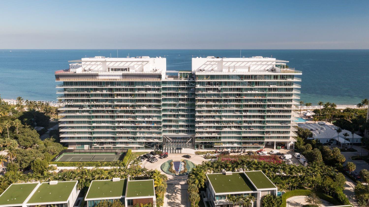 Multi-story residential building featuring extensive glass-fronted terraces, tennis courts, an arrival fountain, and direct waterfront access
