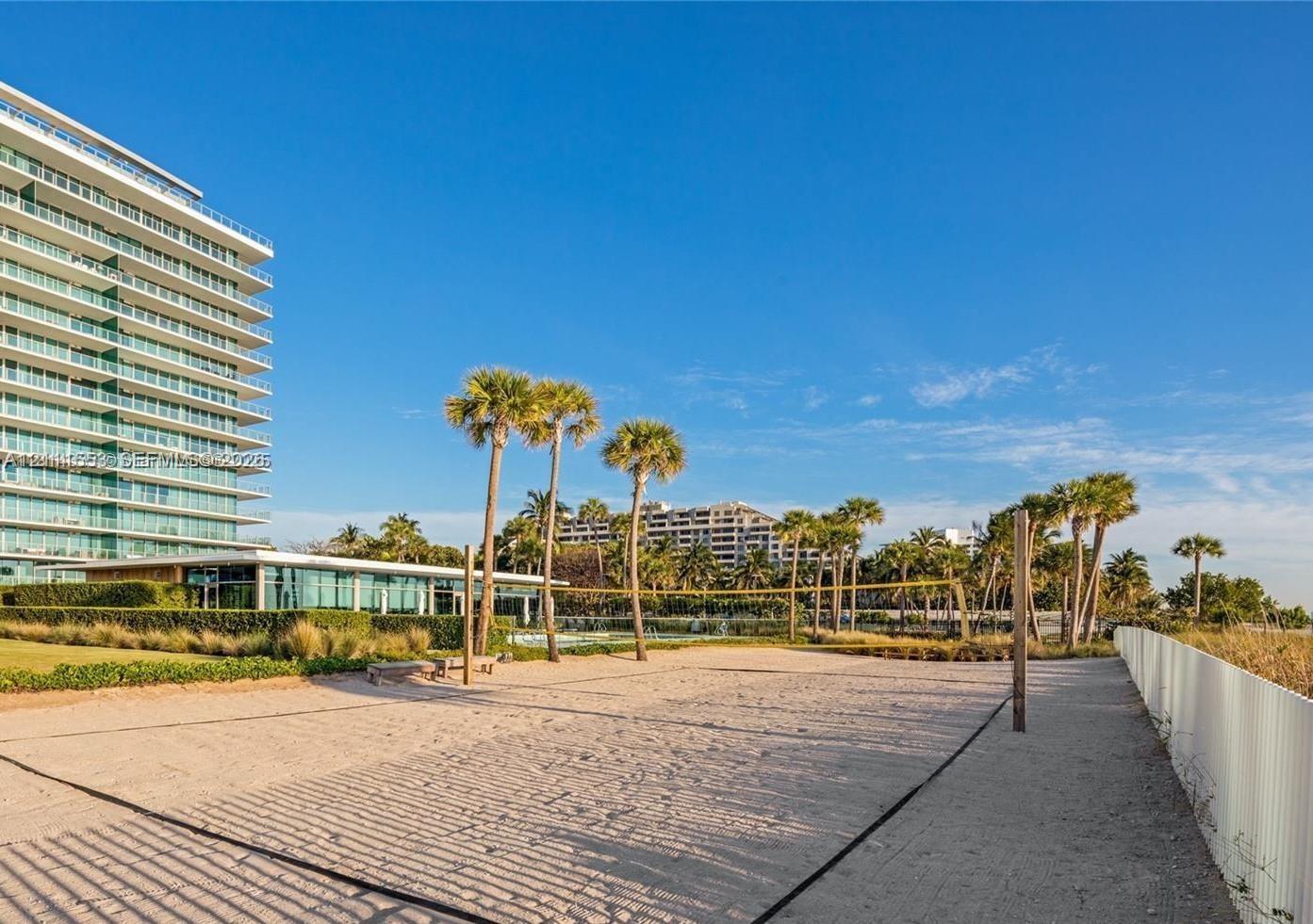 Sand volleyball court featuring a net, perimeter boundary lines, and surrounding palm trees