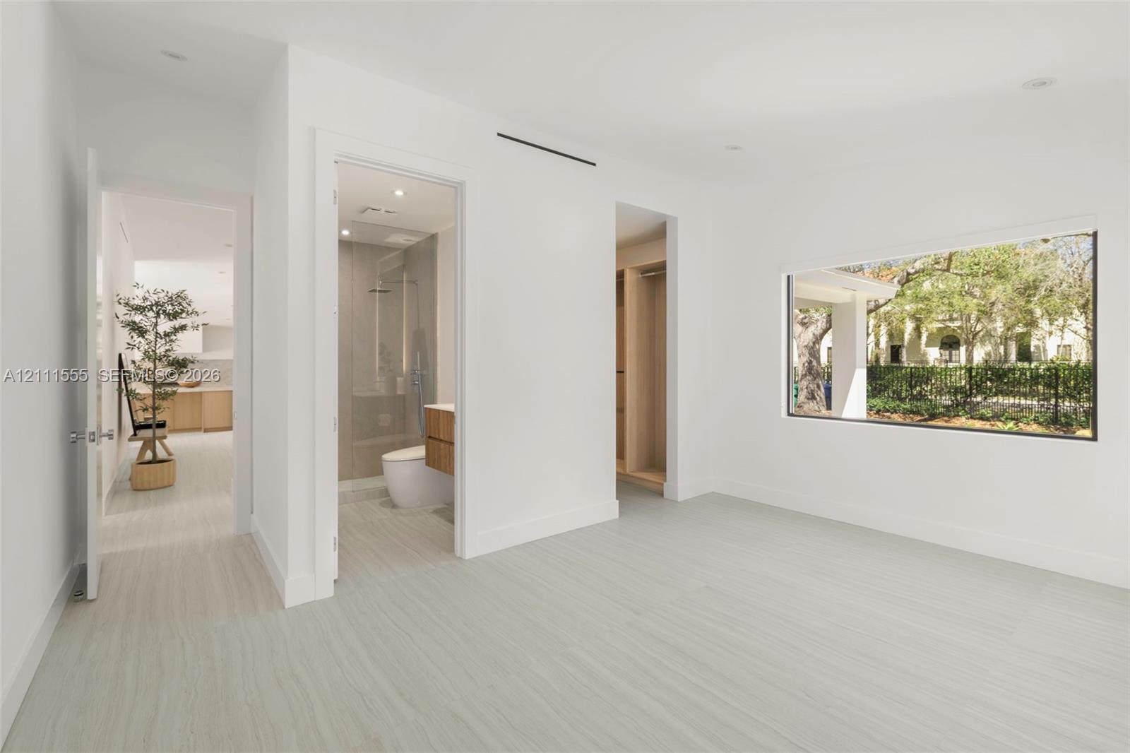 Interior room featuring wood-finish flooring, recessed lighting, expansive picture window, and built-in closet cabinetry Interior room featuring wood-finish flooring, recessed lighting, expansive picture window, and built-in closet cabinetry