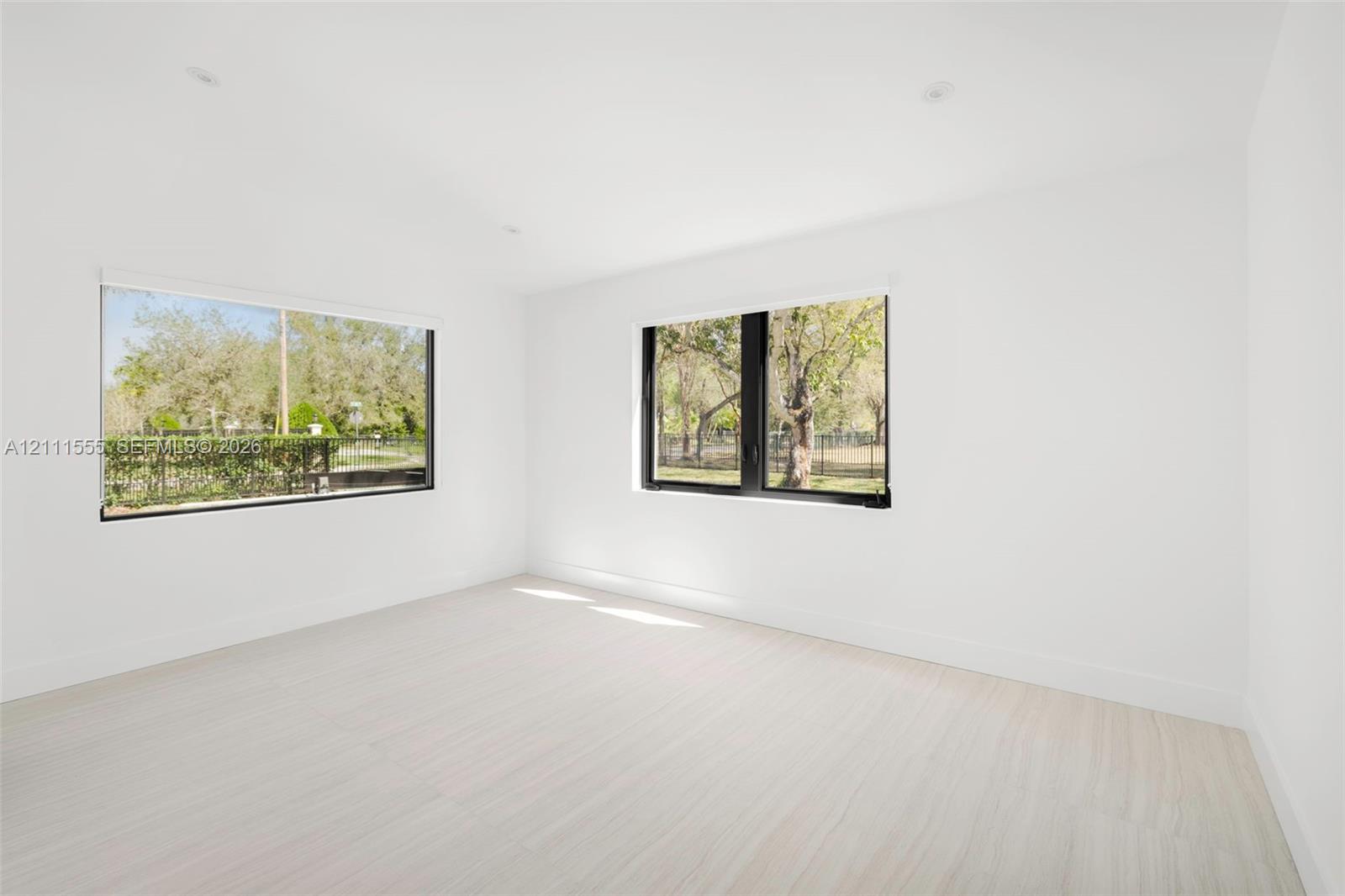 Bright room featuring wood-finish flooring, recessed lighting, and large windows with black frames