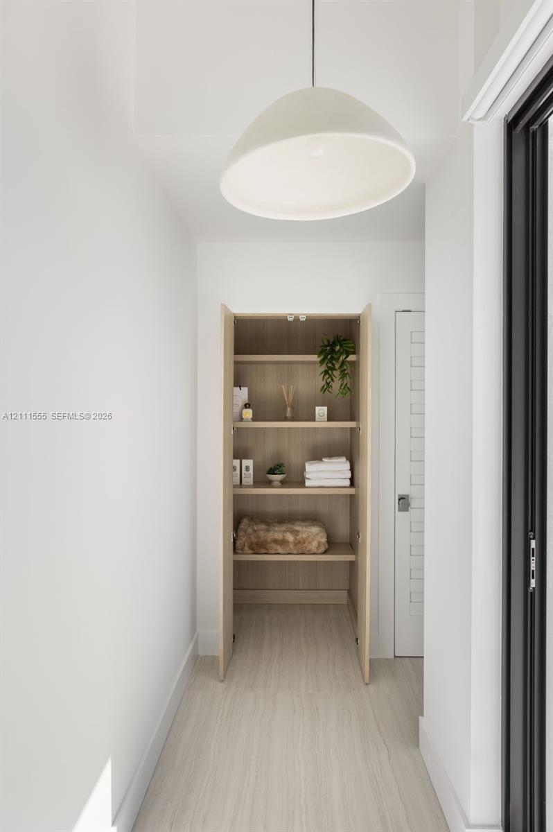Built-in cabinetry featuring natural wood finish, four open shelves, minimalist dome pendant lighting, and wood-finish flooring