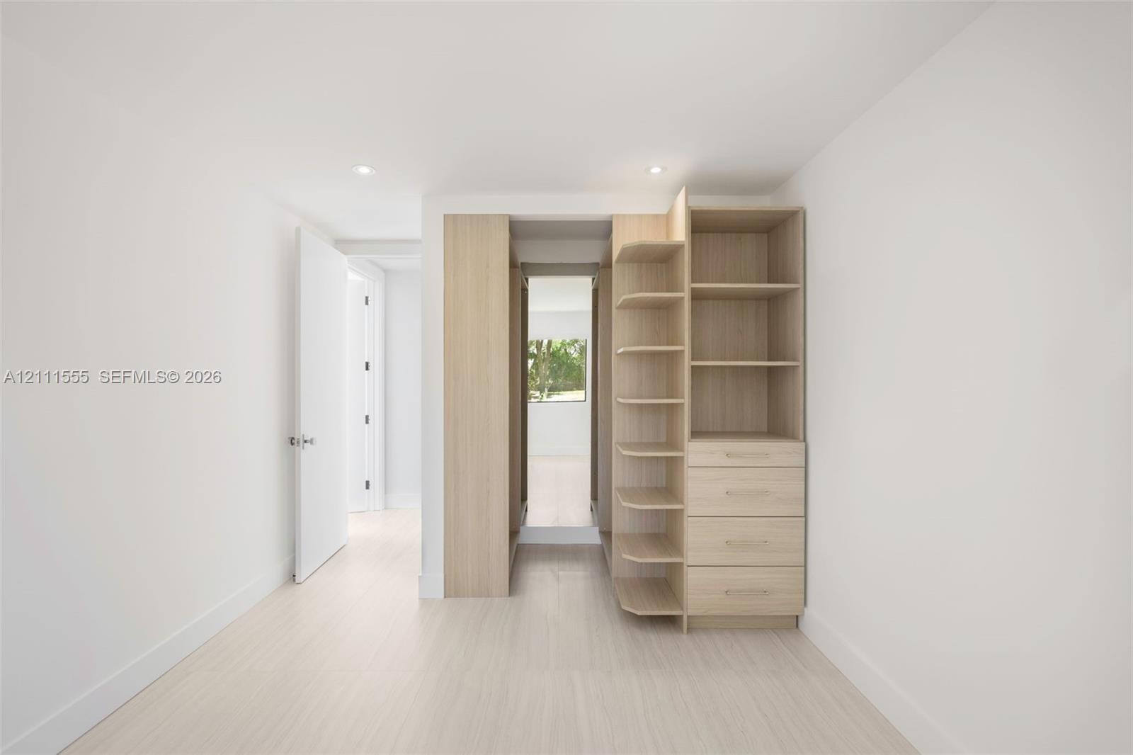 Custom built-in wood-finish cabinetry featuring open shelving and four integrated drawers, recessed ceiling lighting, and wood-finish flooring