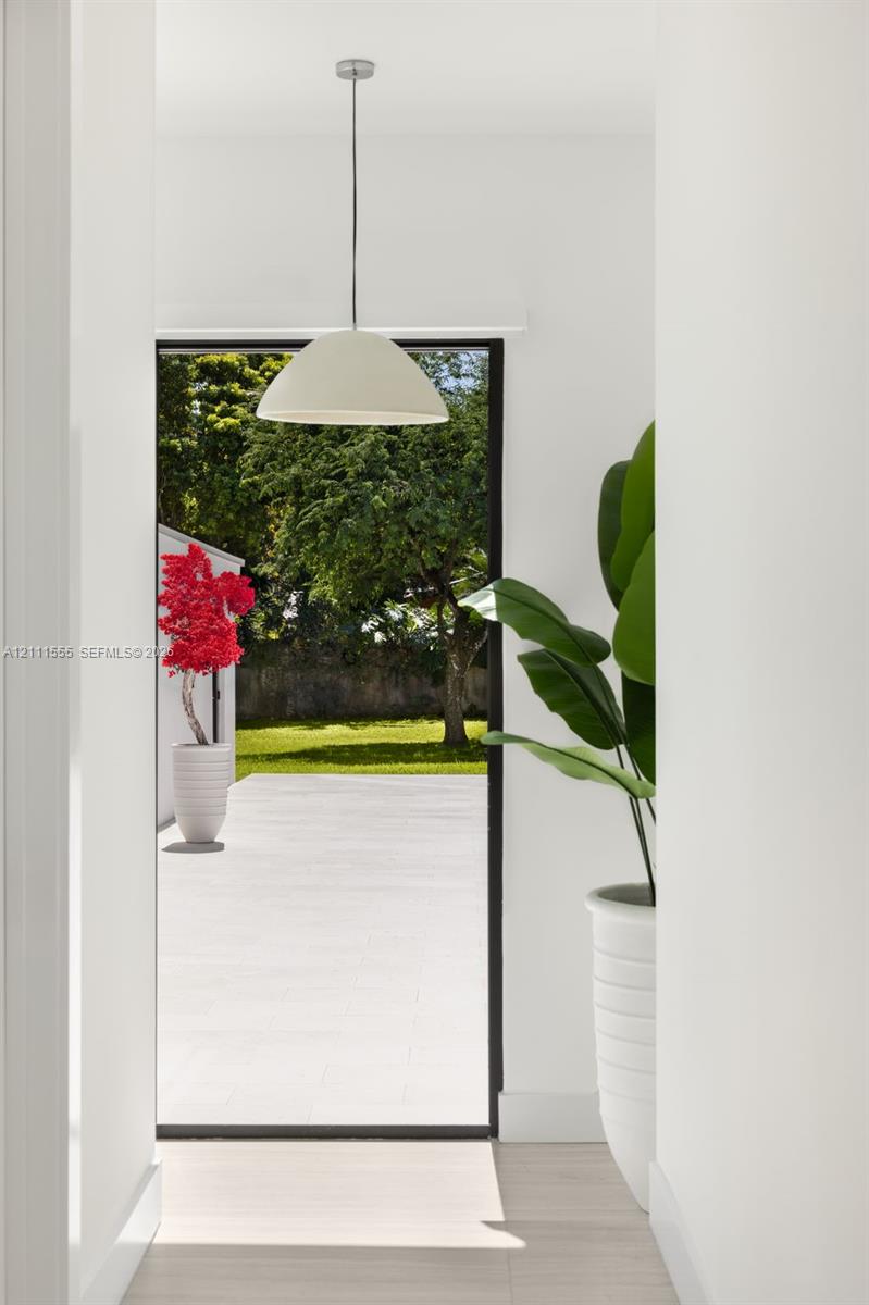 Minimalist pendant lighting, wide-format glass door, and exterior stone patio
