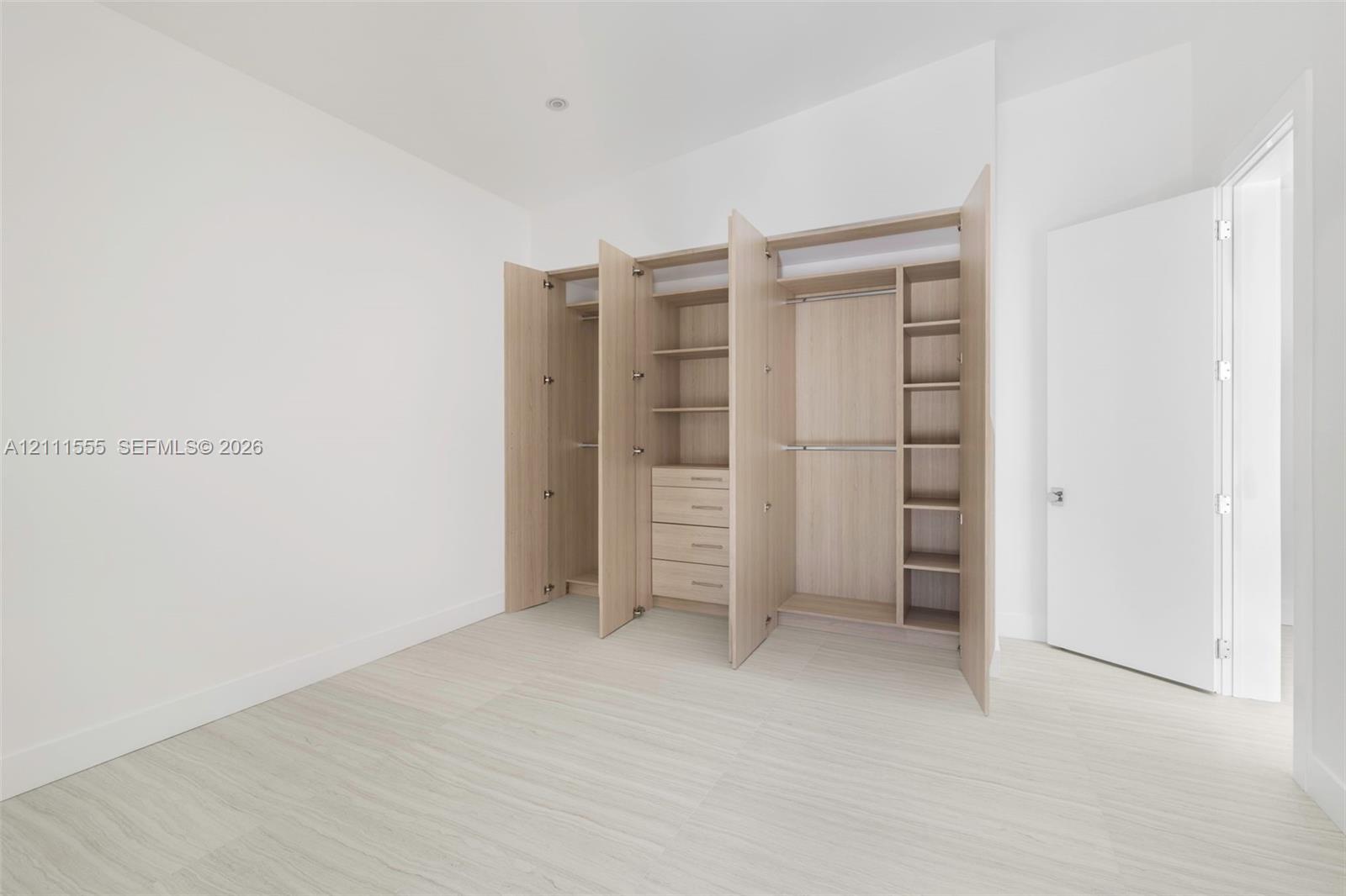 Custom built-in wood-finish cabinetry featuring integrated shelving, hanging rods, and a four-drawer storage unit