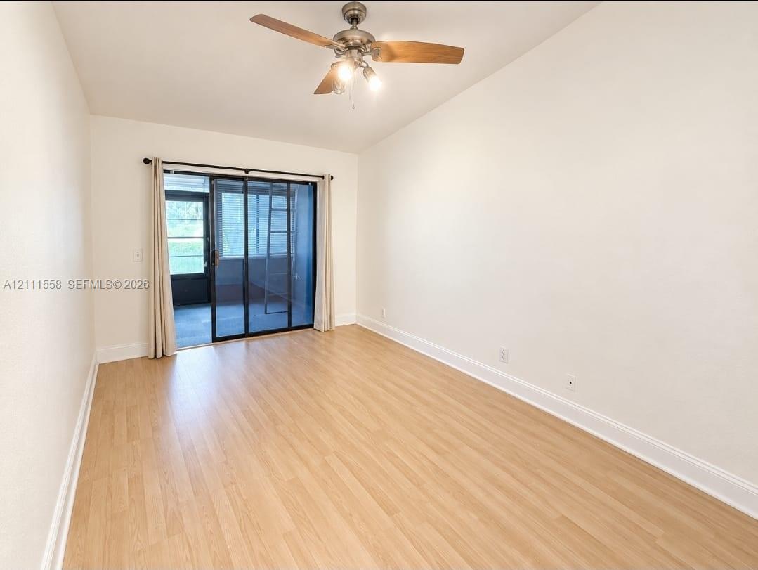 Room featuring wood-finish flooring, a ceiling fan with integrated lighting, and a sliding glass door