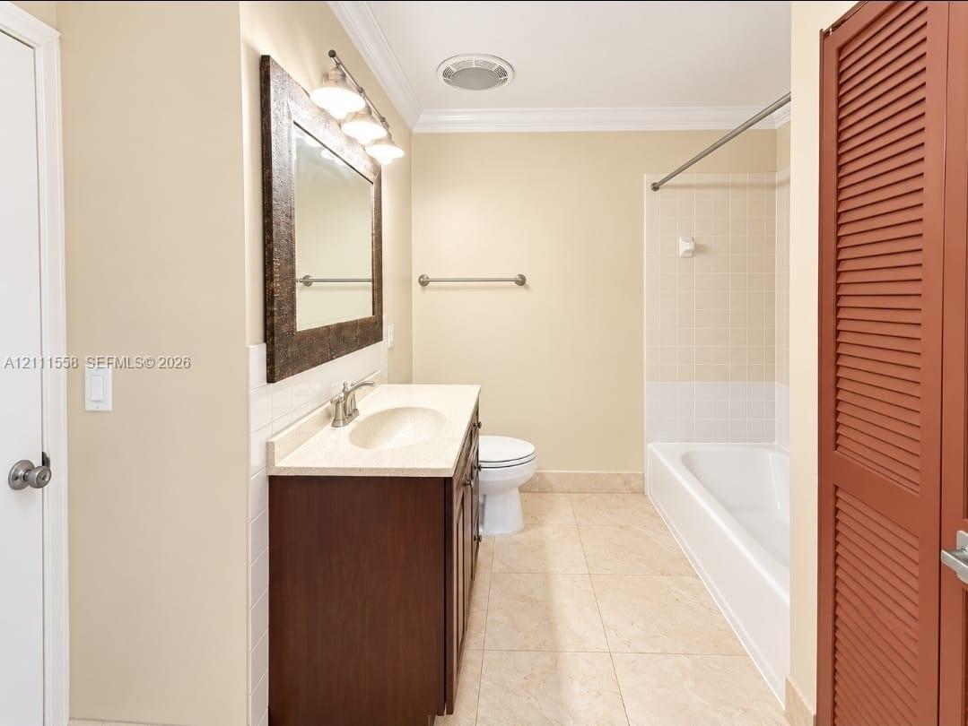 Bathroom featuring a vanity with an integrated basin, a dark wood-finish cabinet, a framed mirror, tile flooring, and a shower-tub combination with tiled walls