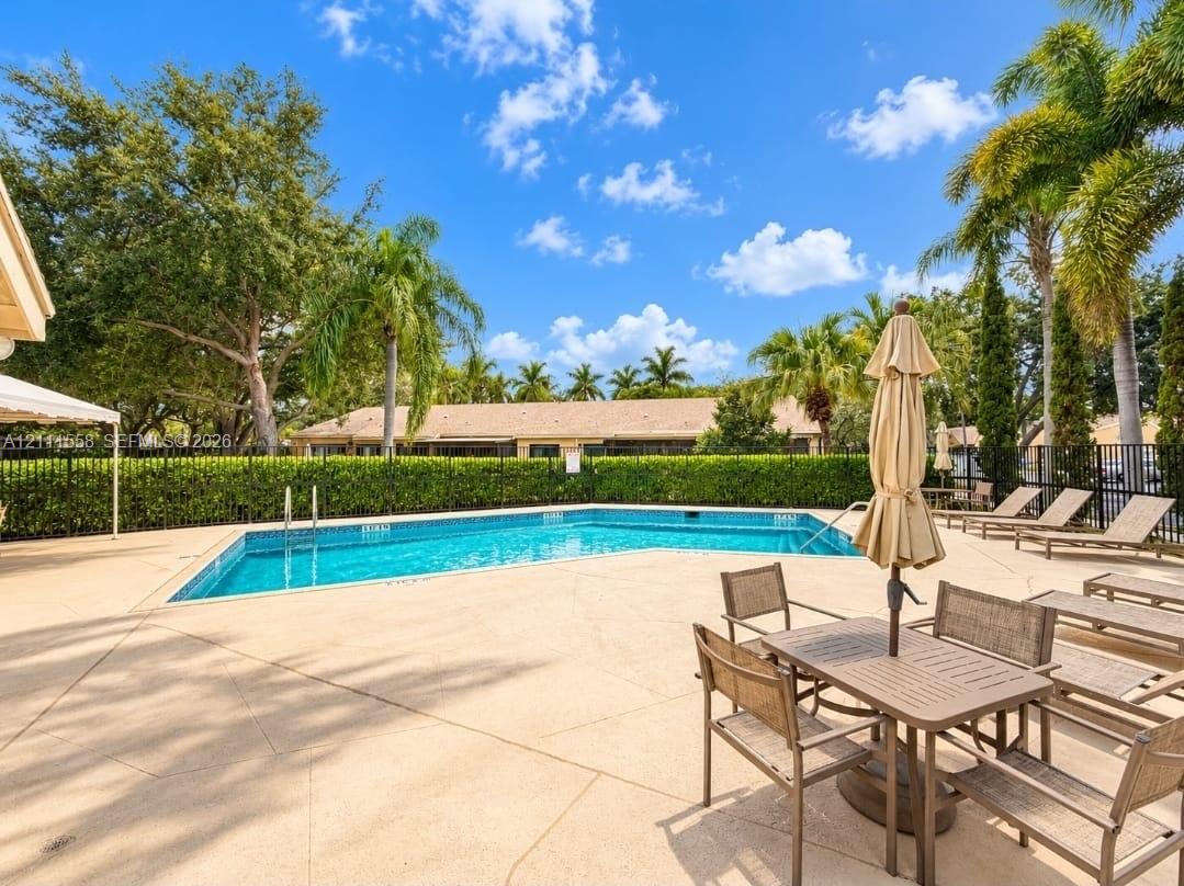 In-ground swimming pool with a concrete pool deck, enclosed by perimeter fencing and landscaped hedging