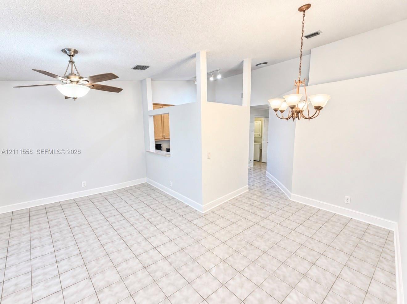 Ceramic tile flooring, vaulted ceilings, multi-arm metal chandelier, and a ceiling fan with integrated light fixture