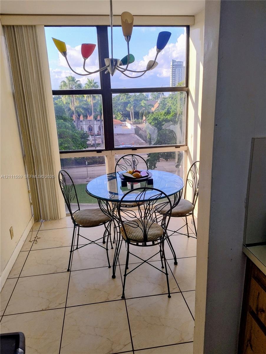 Floor-to-ceiling windows, tile flooring, and multi-colored chandelier featuring polished metal finish