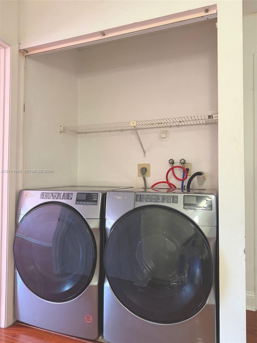 Laundry alcove featuring stainless steel front-loading laundry appliances and a built-in wire shelving unit