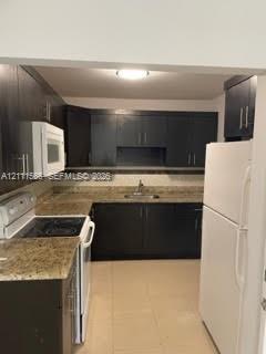 Kitchen featuring dark cabinetry, stone-finish countertops, stainless steel sink with a goose-neck faucet, and ceramic tile flooring Kitchen featuring dark cabinetry, stone-finish countertops, stainless steel sink with a goose-neck faucet, and ceramic tile flooring