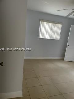 Neutral-toned tile flooring, light gray wall paint, white-panel interior door, and window with vertical blinds Neutral-toned tile flooring, light gray wall paint, white-panel interior door, and window with vertical blinds