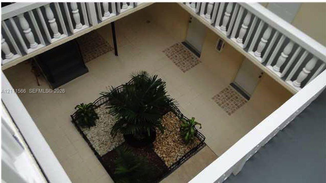 Central courtyard featuring a tiled patio, decorative wrought-iron fencing, tiered gravel garden beds, and a wrap-around railed balcony Central courtyard featuring a tiled patio, decorative wrought-iron fencing, tiered gravel garden beds, and a wrap-around railed balcony