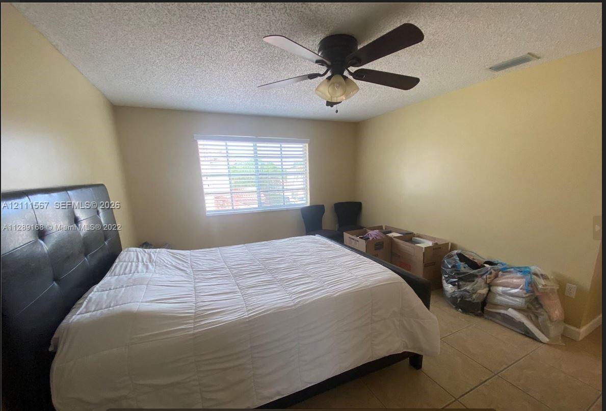 Room featuring tile flooring, ceiling fan with integrated light fixture, and horizontal blind window treatments