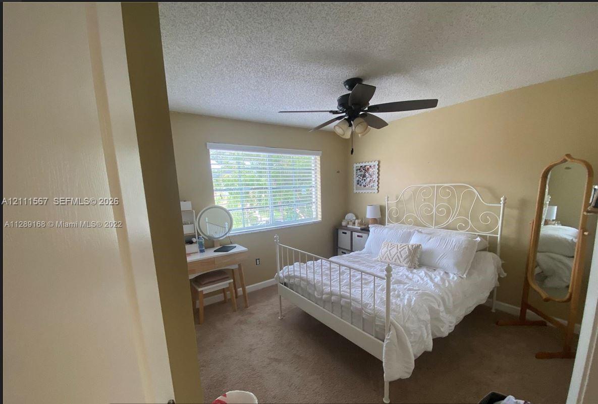 Bedroom featuring neutral wall paint, carpeted flooring, a ceiling-mounted light fixture with a fan, and a single-pane horizontal window