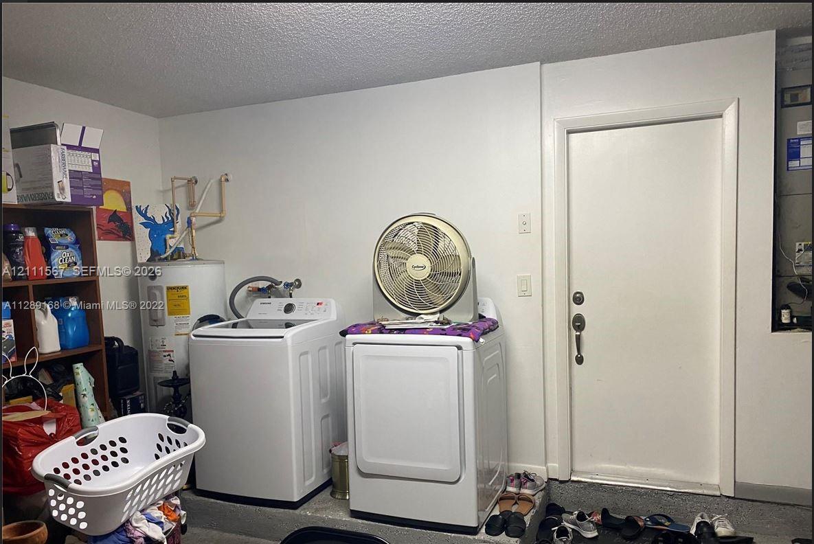 Utility area featuring a cylindrical water heater, dedicated laundry hookups, and a solid-core interior door