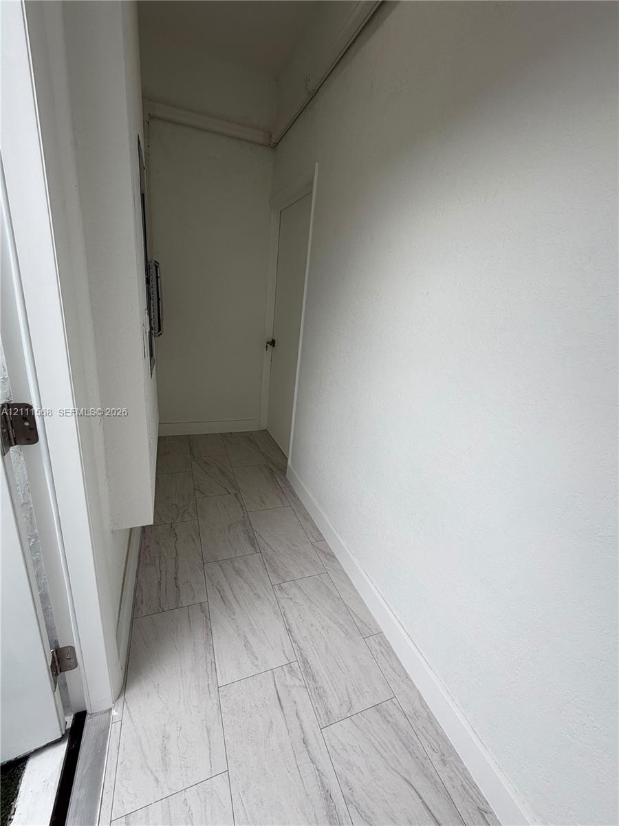Neutral-toned ceramic tile flooring with a linear pattern, painted walls, and a solid-core swing door