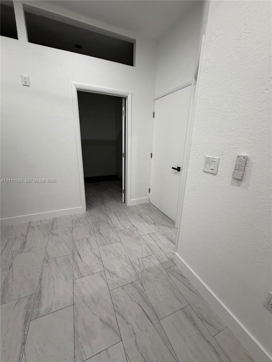 Neutral color palette featuring high-contrast tile flooring, soaring ceilings with rectangular transom windows, and crisp white wall finishes