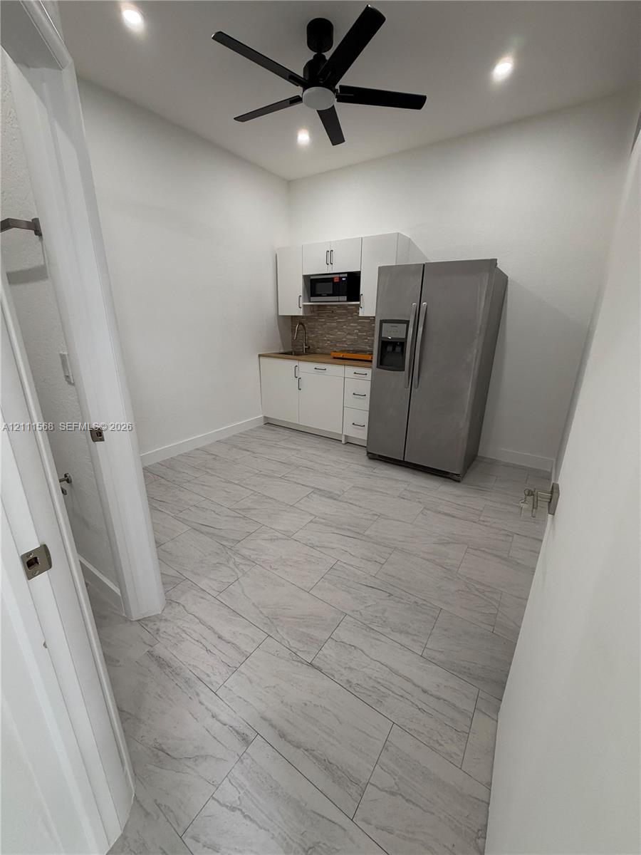 Kitchen area featuring wood-finish tile flooring, white cabinetry, a tiled backsplash, and recessed lighting with a central ceiling fan