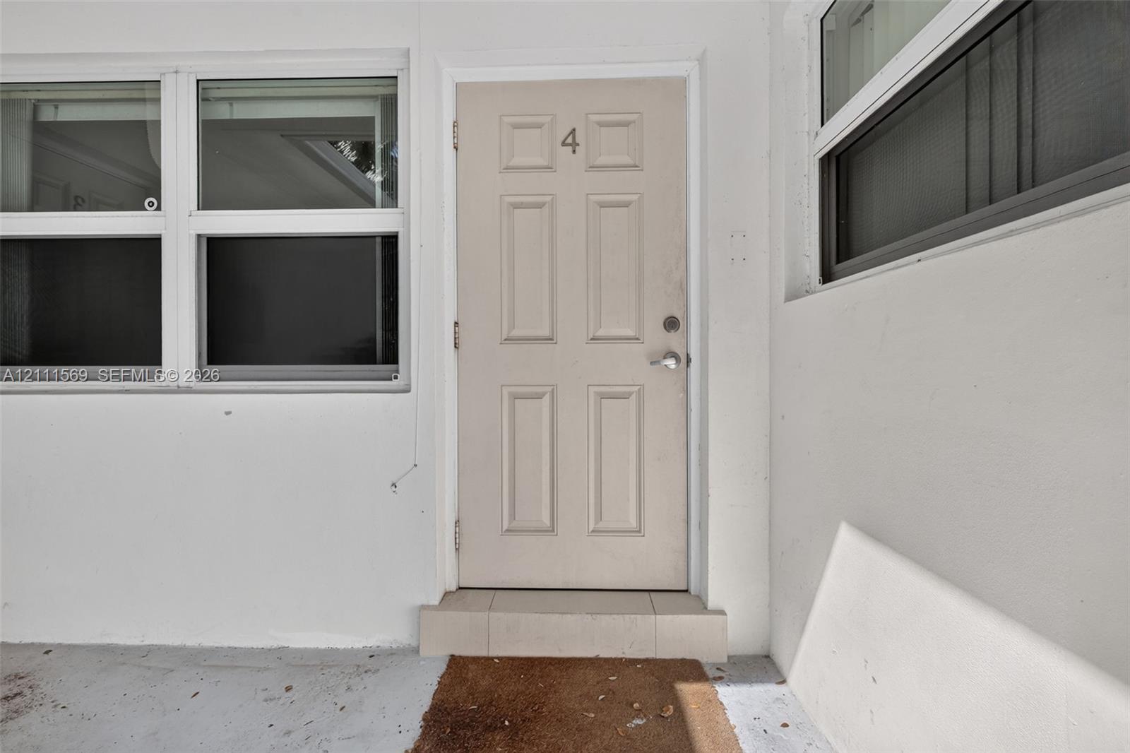 Entry featuring a neutral-toned, six-panel door with metallic hardware, accented by large multi-pane windows and a tiered exterior threshold