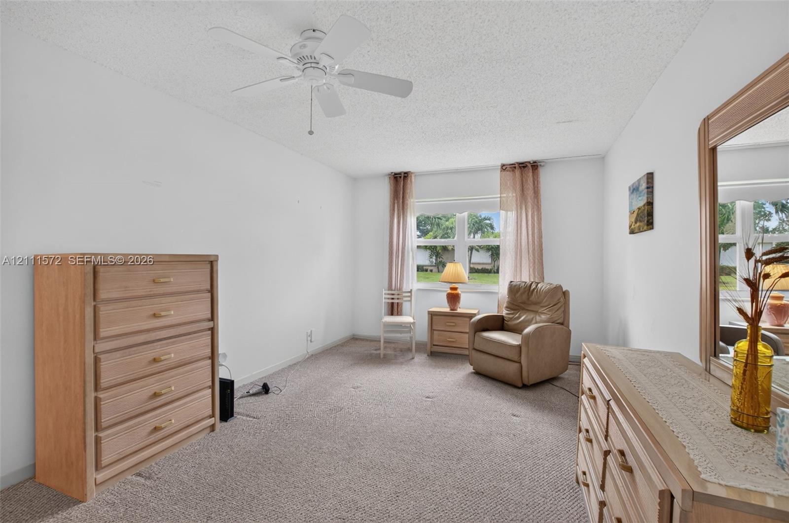 Neutral-toned berber carpeting, large impact windows providing natural light, energy efficiency, and sound proofing, and a ceiling fan