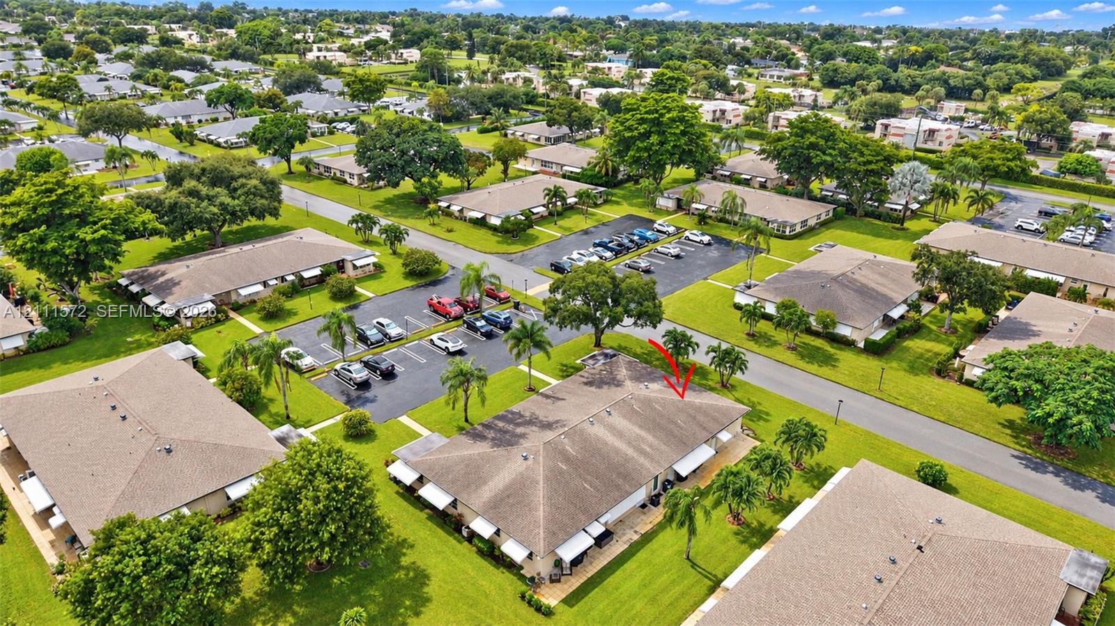 Aerial perspective of a single-story residence featuring a shingled roof, attached exterior awnings, and manicured surrounding lawn area