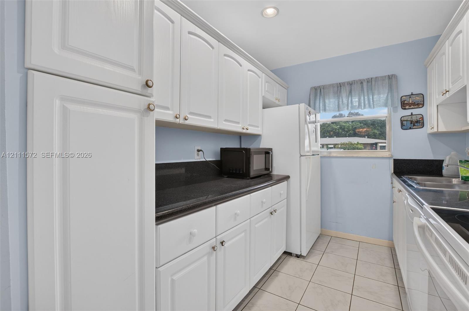 Kitchen featuring white cabinetry, stone-surface countertops, tile flooring, and recessed lighting