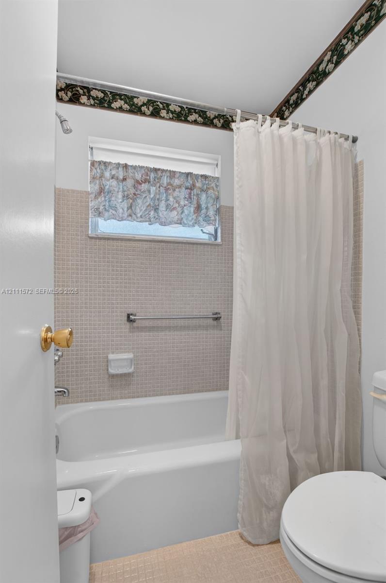 Bathroom featuring a white porcelain tub, square-tiled wall